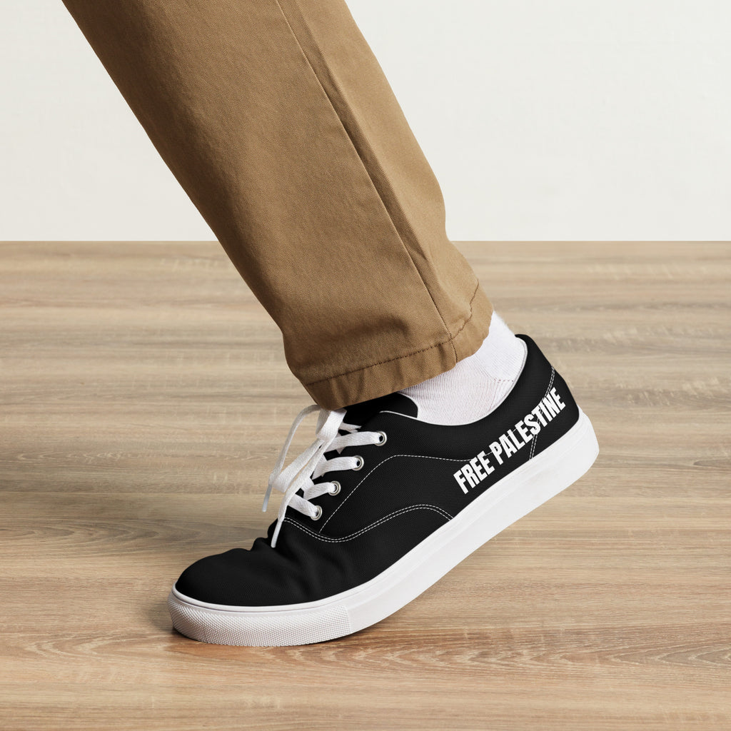 Black Free Palestine canvas sneakers worn by a model, showing bold white side lettering